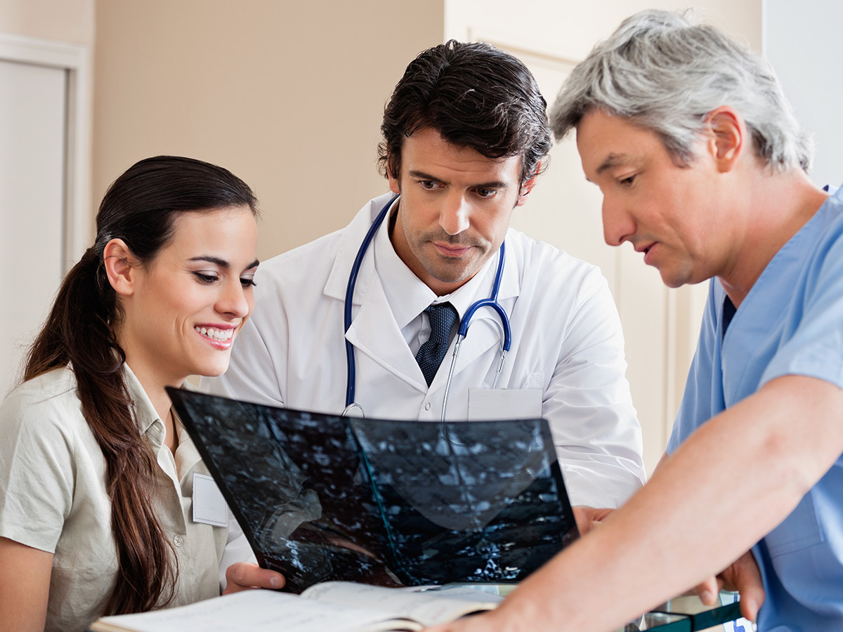 Medical professionals reviewing x-ray at hospital reception.