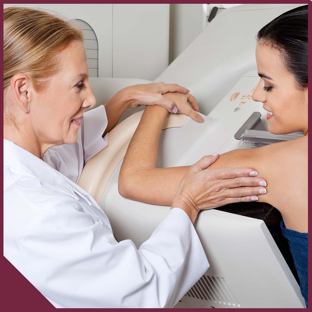 Mature female doctor assisting young patient during mammography.