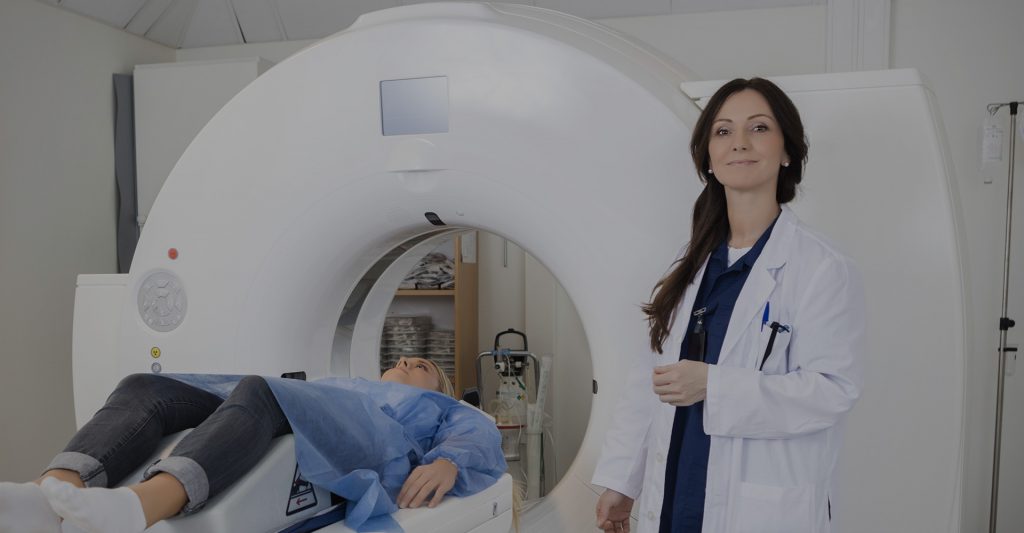 MRI doctor standing next to machine and patient