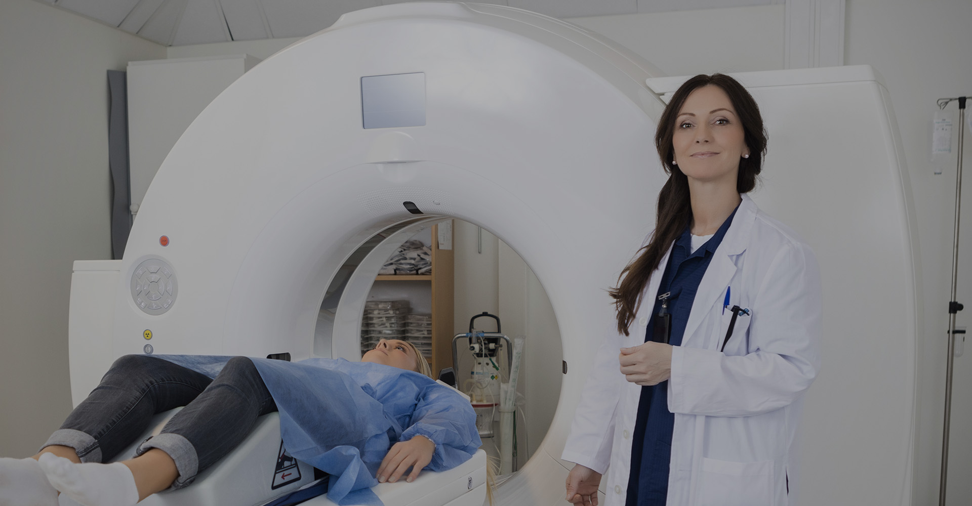 MRI doctor standing next to machine and patient