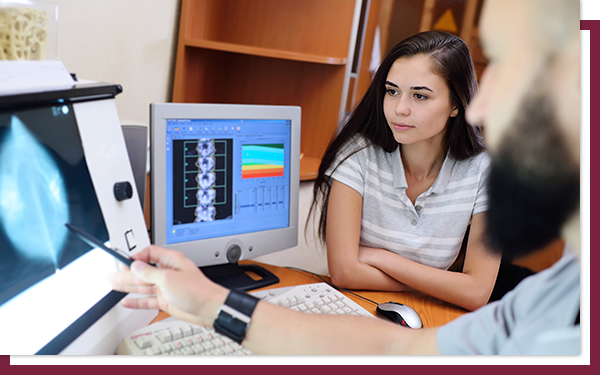 A radiologist showing a young patient an ultrasound view of her breast.