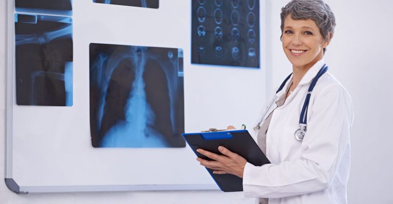 A radiologist standing next to x-rays.