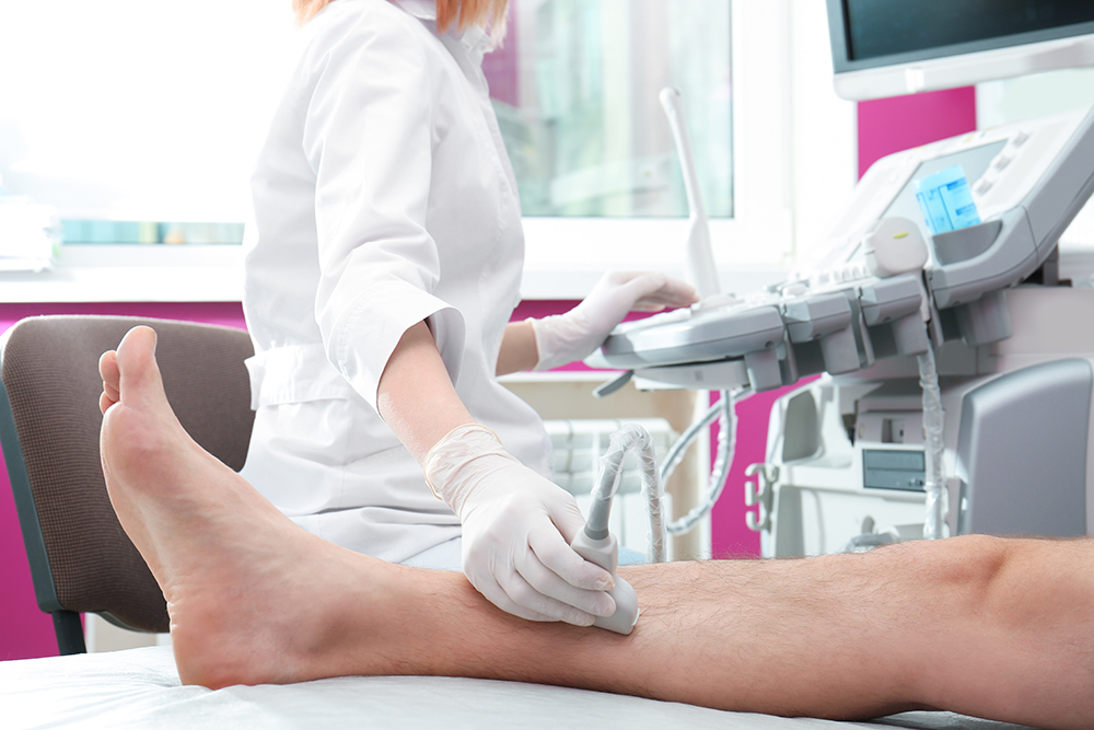 Doctor conducting ultrasound examination of patient's leg in clinic, closeup