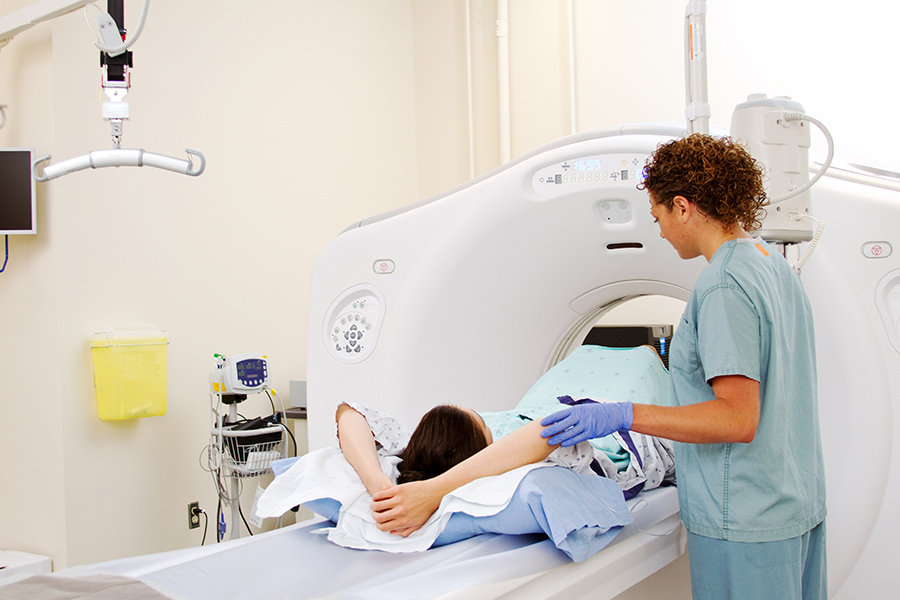 a woman in an open MRI machine with a nurse assisting them