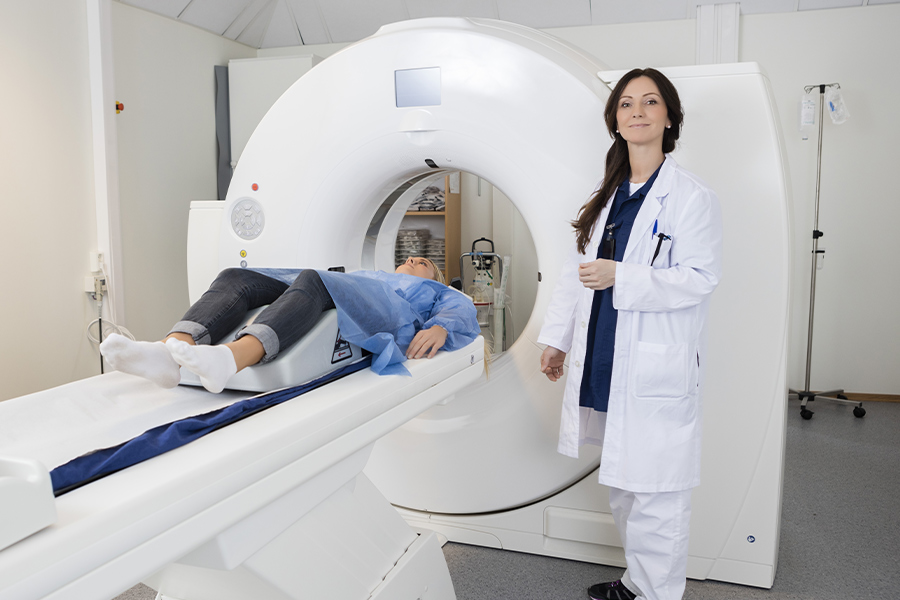 a person laying in an MRI machine with a happy doctor standing beside them
