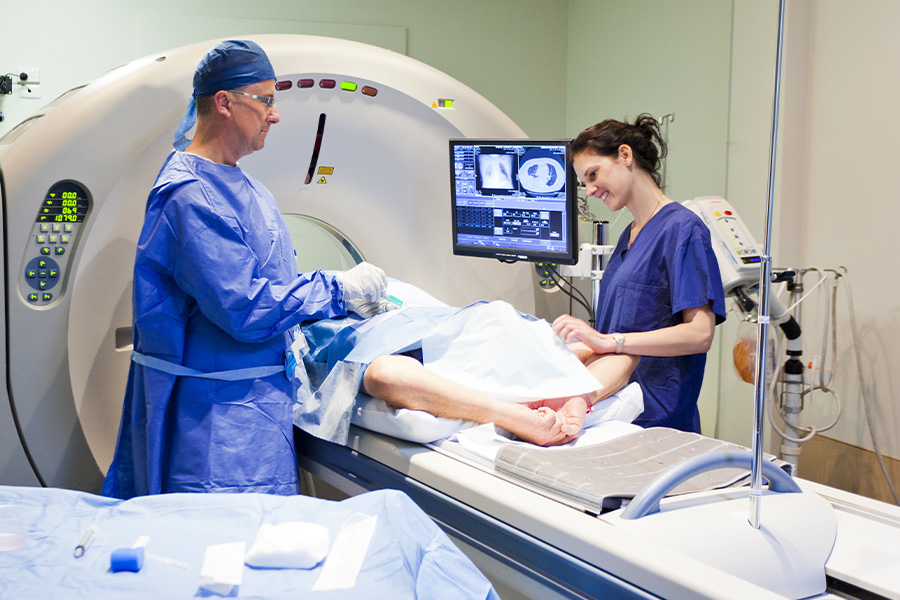 a person in an MRI machine while a doctor and nurse look at images of their small intestine