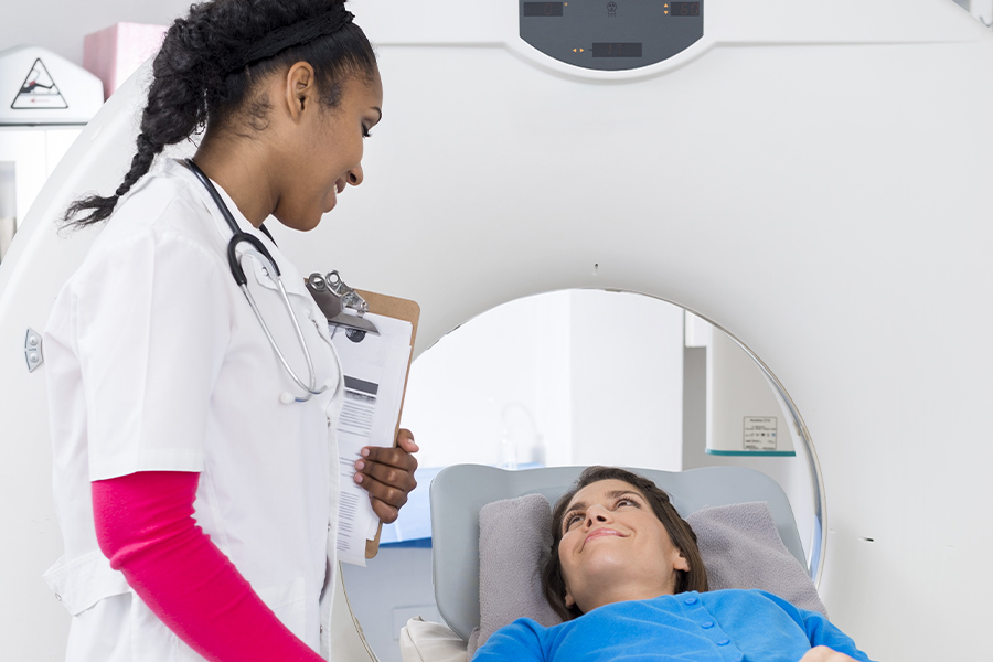 a person laying on an MRI bed smiling up at a happy doctor